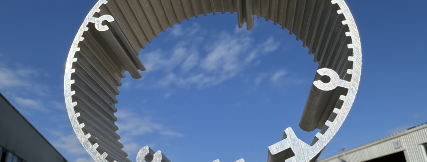 A circular, hollow aluminium heat sink against a sunny, blue sky from a low angle pointing skyward